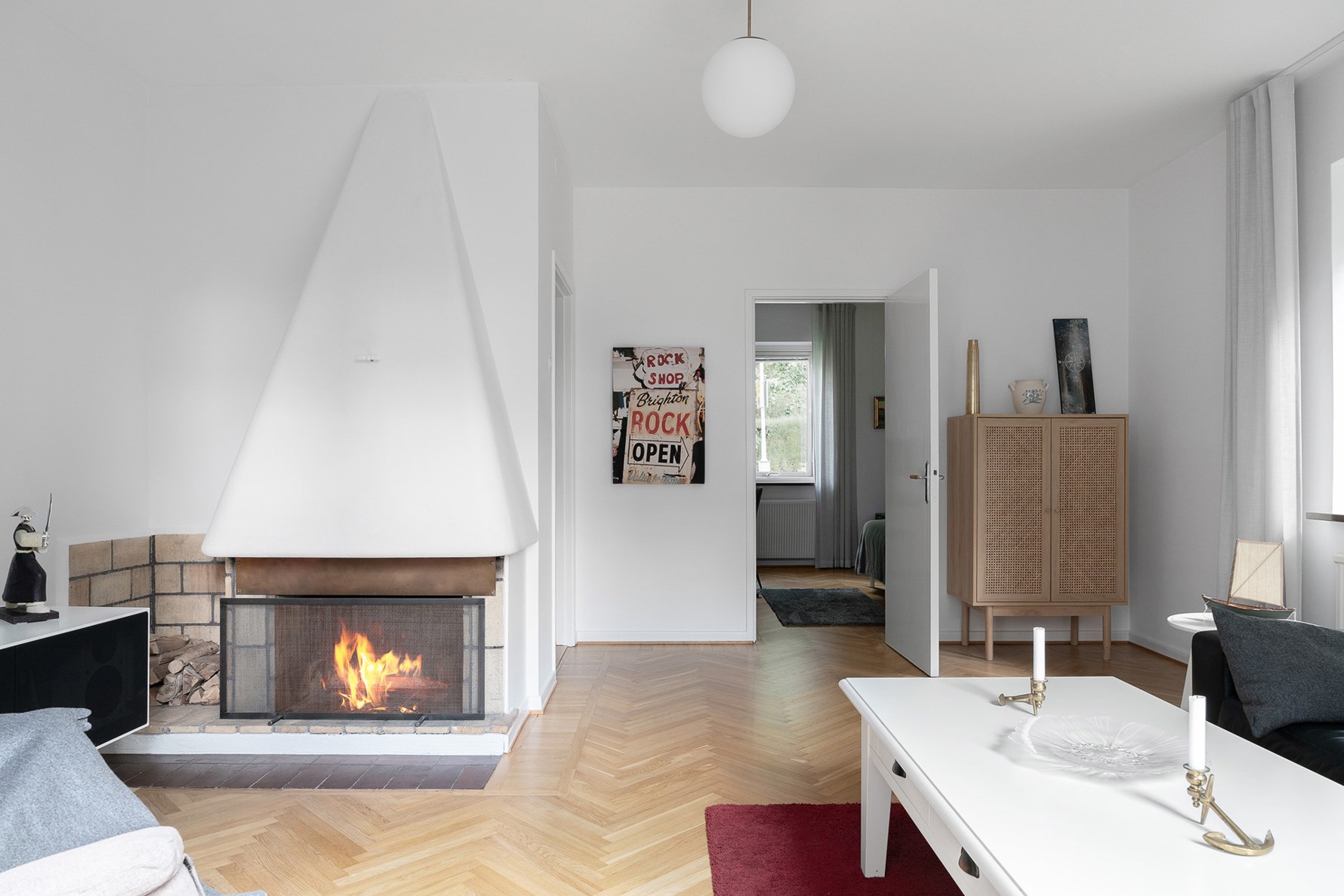 Fungerande öppen spis med vedförvaring intill som smyckar rummet